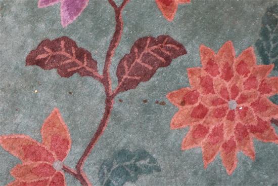 A Chinese carpet, the centre woven with flowering prunus and other shrubs on a celadon ground, within 477 x 385cm